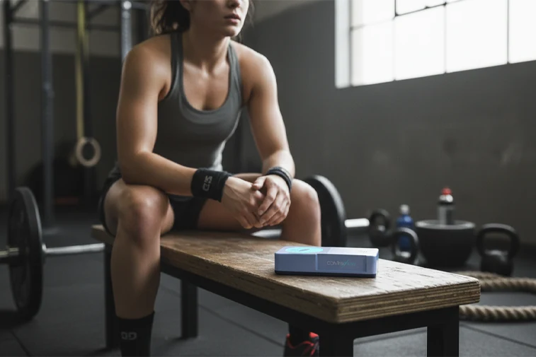 An athlete in a gym with coMra Flow on the bench